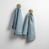 Austin Guest Towel | Tahoe Blue | midweight linen guest towels in tahoe blue on towel hooks mounted to a white wall.