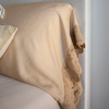 a close up of madera luxe fitted sheet and lace trimeed pillowcase in warm neutral tones.