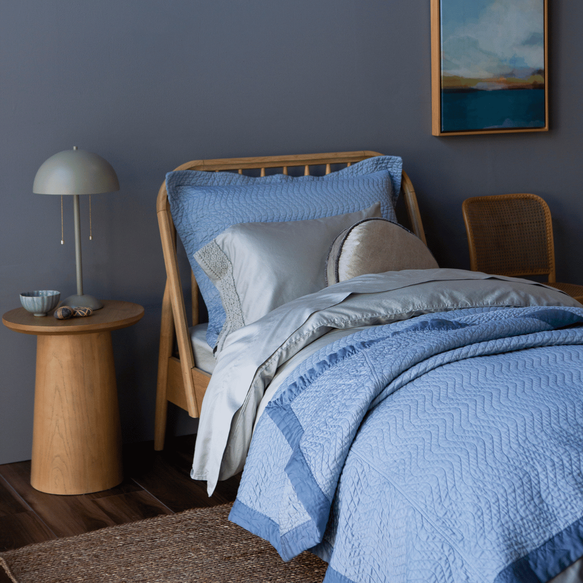 [allvariants]: a twin bed shown from an angle dressed mostly in monochromatic tones, the flat sheet is folded back over the duvet cover which is pulled back over the coverlet. 