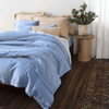 Linen Duvet Cover | [allvaraints] | an all linen bed in blue and honey colored bedding shown against a wall (no headboard) with a coordinating side table and rug finish the light and airy room.