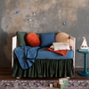 Cirillo Baby Blanket | A colorful crib shown with wooden blocks on the rug and a sailboat on the side table. Shot against a limewash wall and dark wooden floor. 