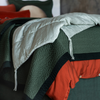 Taline Blanket | a close up of a charmeuse ed end blanket with tassels t the foot of a colorful bed.