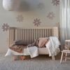 Madera Luxe Crib Sheet | a pale pink crib sheet dressed with other pink, grey and warm white tones in a natural wooden crib styled as a toddler bed against a wall with large flower decals.