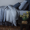 Madera Luxe Duvet Cover | Tahoe Blue | a monochromatic bed in blue tones shown from the side with a side table holding a green vase and botanical.