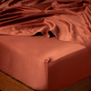 Bria Twin Flat Sheet | Autumn | A close-up of a bed corner in a Bria fitted sheet in Autumn, a rich terracotta tone.