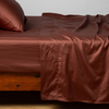 Bria Twin Flat Sheet | Autumn | A close-up side view of a bed with the Bria flat sheet with the matching sham and pillow in Autumn, a rich terracotta tone.