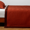 Cirillo Twin Coverlet | Autumn | A close-up side view of a bed with our Cirillo coverlet and a matching pillowcase in Autumn, a rich terracotta tone.