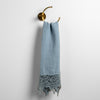 Frida Guest Towel | Tahoe Blue | Lace trimmed linen guest towel  draped through a decorative towel crescent ring against a plain white background.