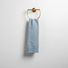 Ines Guest Towel | Tahoe Blue | guest towel draped through a decorative brass towel ring against a white background.