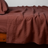 Linen Twin Fitted Sheets | Autumn | A close-up side view of a bed with the Linen flat sheet with the matching sham and pillow in Autumn, a rich terracotta tone.