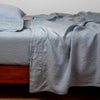 Linen Flat Sheet | Tahoe Blue | fitted sheet with matching rumpled flat sheet and sleeping pillow - side view.