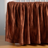 Autumn | A close-up side view of a crib with the Paloma crib skirt in Autumn, a rich terracotta tone.